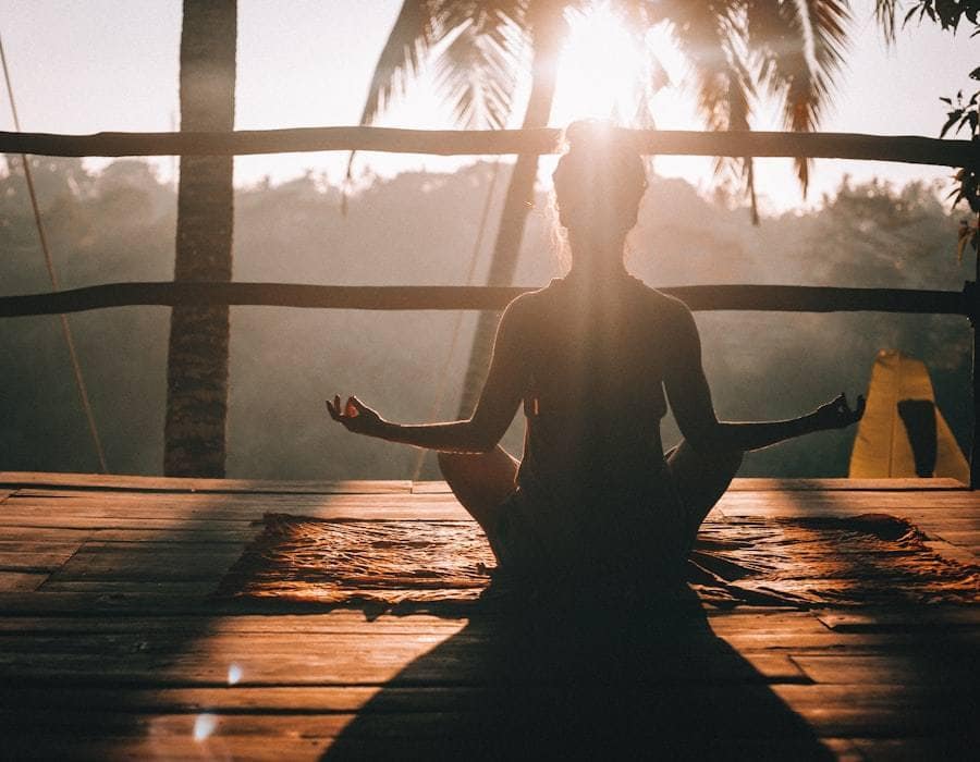 A person sitting quietly in meditation as the sun sets