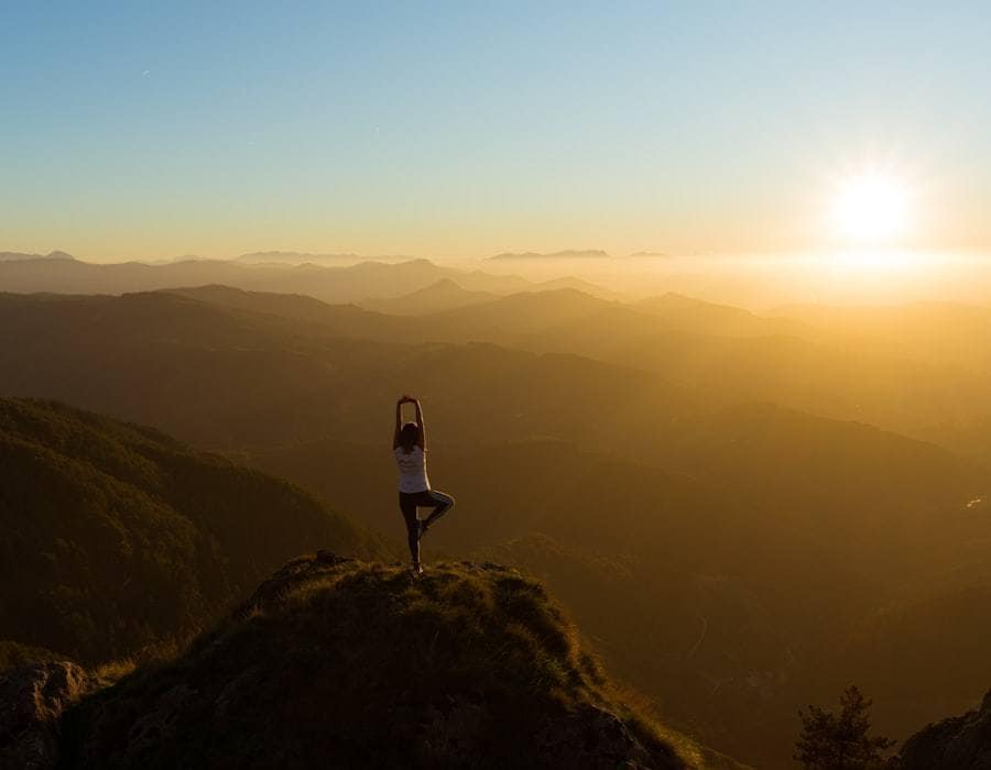 A lone figure on a hilltop watching the sun rise